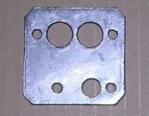 Metallplatte mit mehreren Löchern in unterschiedlichen Durchmessern, vermutlich Teil einer Dichtung oder Dichtungsanwendung. Marke: Remeha.